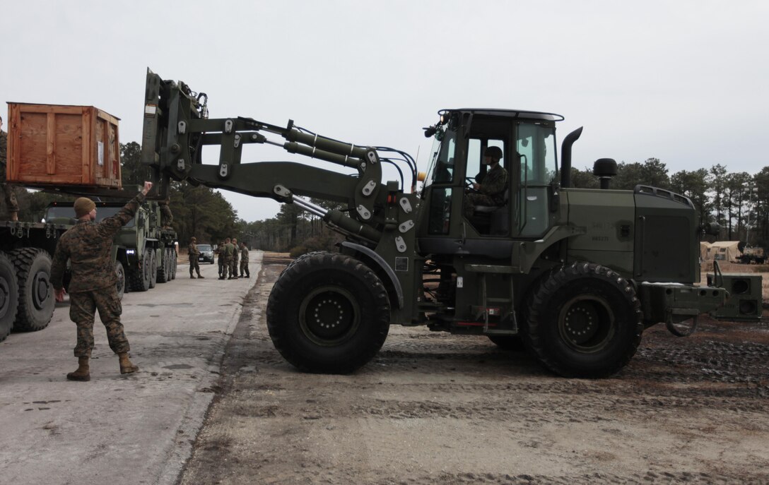 Lance Cpl. Daniel Skora signals Lance Cpl. Aaron Stidham to stop lifting a crate at Marine Corps Outlying Field Atlantic, N.C., Feb. 25, 2015. More than 100 Marines with 2nd Marine Aircraft Wing at Marine Corps Air Station Cherry Point, N.C., participated in exercise Lagoon Breach, an integrated exercise conducted to test Marines ability to operate in an austere environment and practice their field expediency.  Skora is an engineer equipment electrical systems technician and Stidham is an engineer equipment operator, both with Marine Wing Support Squadron 271 at Cherry Point.  