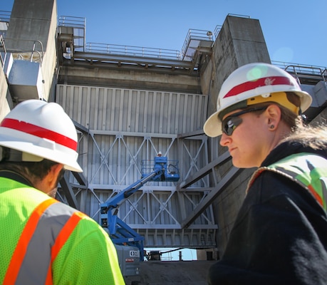 Shauna England Weinmann (right) and Richard Marmolejo with the U.S. Army Corps of Engineers Sacramento District oversee painting of one of three Tainter gates March 3, 2015, at the district's 52-year-old dam at New Hogan Lake in Valley Springs, California. A $6.7 million project will replace nearly every moving part except the large, curved panels of the Tainter gates themselves— including additions such as environmentally-friendly paint and lighting, new water seals, and an electric hoist system. 