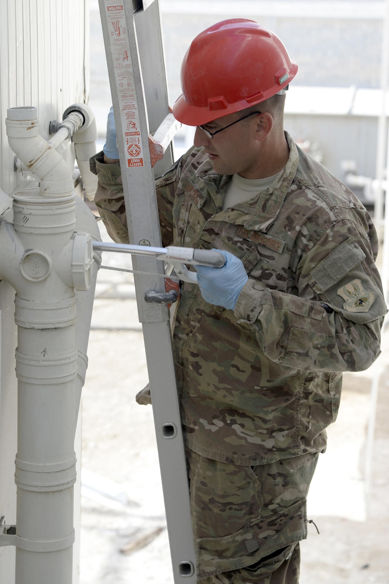 Tech. Sgt. Ronald, Expeditionary Prime Base Engineer Emergency Force Squadron water and fuels systems manager, cuts polyvinyl chloride pipe to an old shower cadillac at an undisclosed location in Southwest Asia Mar. 2, 2015. The EPBS has been working on several base projects to include replacing $280K worth of new showers in the Army barracks. Ronald is currently deployed from the 434th Civil Engineer Squadron out of Grissom Air Reserve Base, Indiana. (U.S. Air Force photo/Tech. Sgt. Marie Brown) (RELEASED)