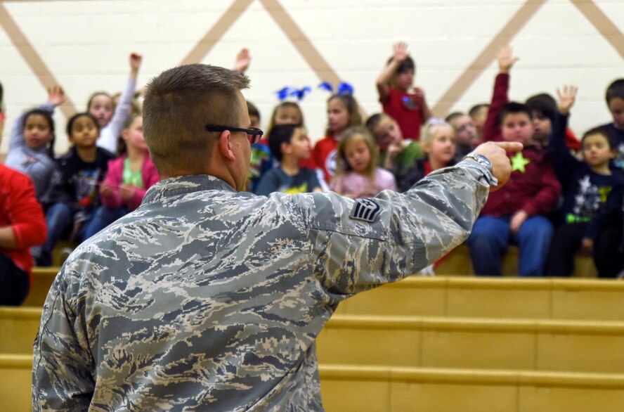 Staff Sgt. Christopher Michaud, 799th Security Forces Squadron military working dog kennel master, answers questions during a K9 demonstration March 2, 2014, inside the Indian Springs Schools gymnasium.  The demonstration was part of a Nevada Reading Week event for Indian Springs Elementary School students. (U.S. Air Force photo by Tech. Sgt. Shad Eidson/released)