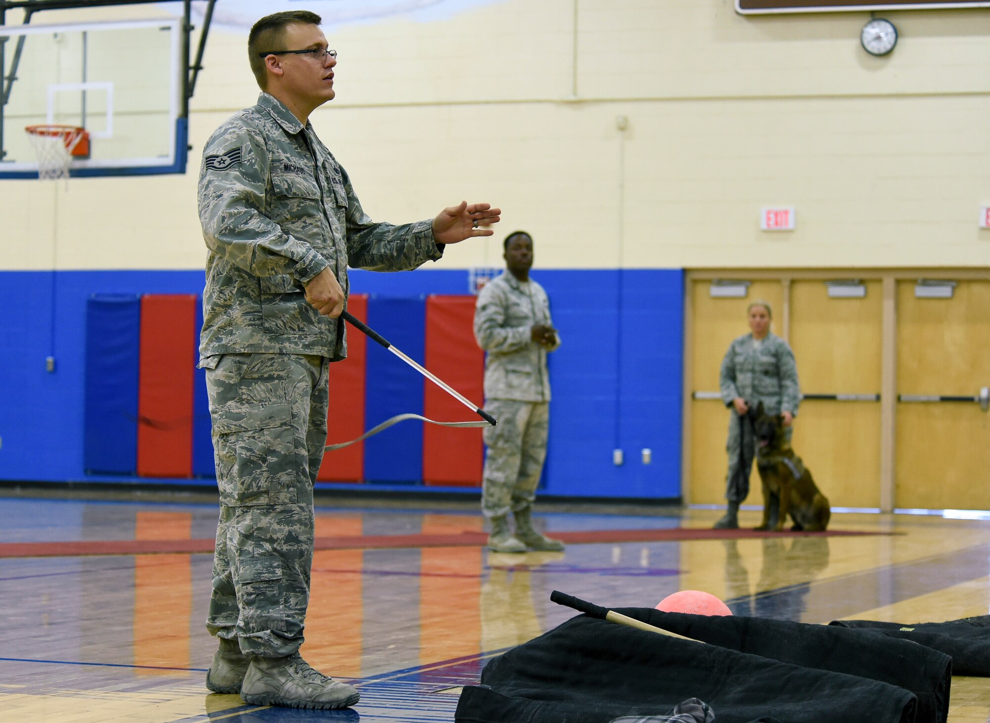 Staff Sgt. Christopher Michaud, 799th Security Forces Squadron, military working dog kennel master, explains the uses of several MWD training tools during a K9 demonstration March 2, 2014, inside the Indian Springs Schools gymnasium. The demonstration was part of a Nevada Reading Week event for Indian Springs Elementary School students. (U.S. Air Force photo by Tech. Sgt. Shad Eidson/released)
