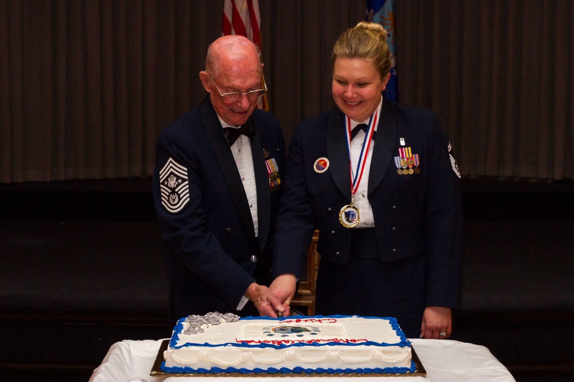 Former Chief Master Sgt. of the Air Force James McCoy and Senior Master Sgt. Emily Shade, Air Force Enlisted Heritage Research Institute director, cut the cake during the Chief Induction Ceremony, symbolizing the most senior and most junior chief master sergeants at the ceremony.  10 Airmen were recognized during the ceremony for rising to the highest enlisted rank of chief master sergeant.  (Air Force photo by Staff Sgt. Christopher Morgan, Air Force Life Cycle Management Center/Cleared)