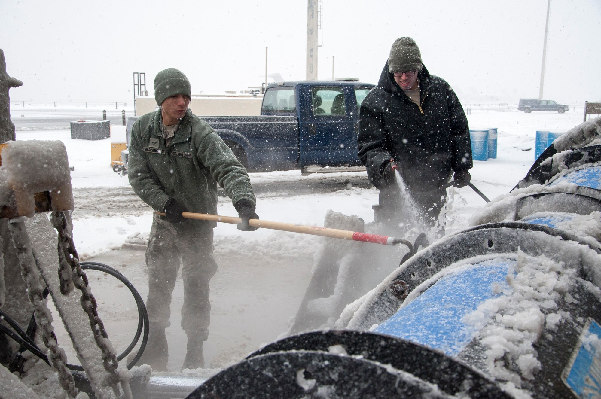 Airman 1st Class Nicholas Marcangelo,  and Airman 1st Class Jeremy Johnson, 436th Civil Engineer Squadron snow operations, clean snow off of a plow in need of repairs March 5, 2015, at Dover Air Force Base, Del. Marcangelo is an electrician and Johnson works in pest management but both are assigned to “snow patrol” from February until snow season ends in late April. (U.S. Air Force photo/Senior Airman Jared Duhon)