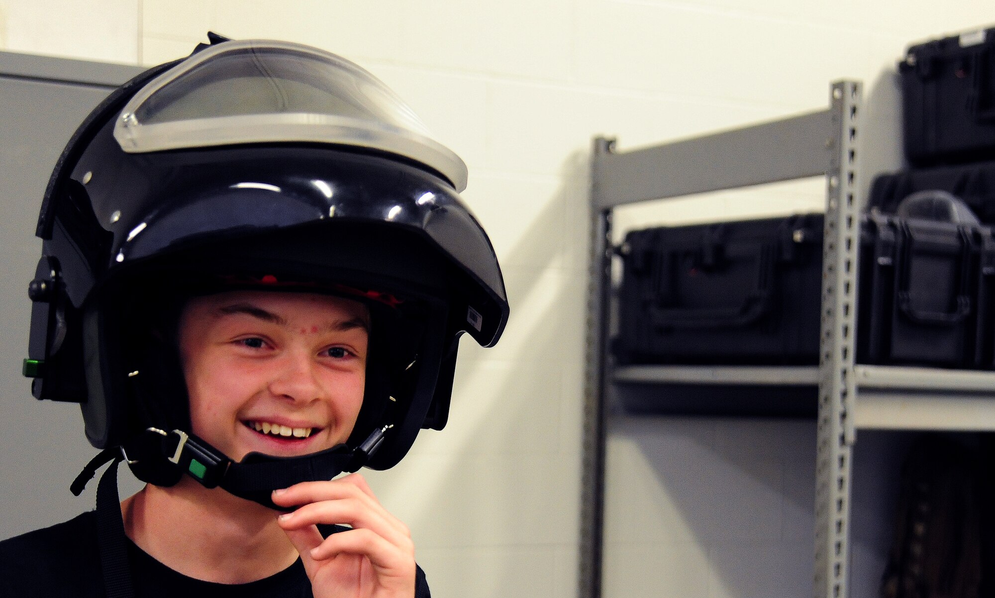 Gage Baska, a 14 year-old resident of Blue Springs, Mo., straps on an explosive ordinance disposal helmet at Whiteman Air Force Base, Mo., Nov. 5, 2014. Baska had an opportunity to tour the EOD training area and learn about various functions of the career field as part of an intervention program he is participating in. (U.S. Air Force photo by Staff Sgt. Nick Wilson/Released)