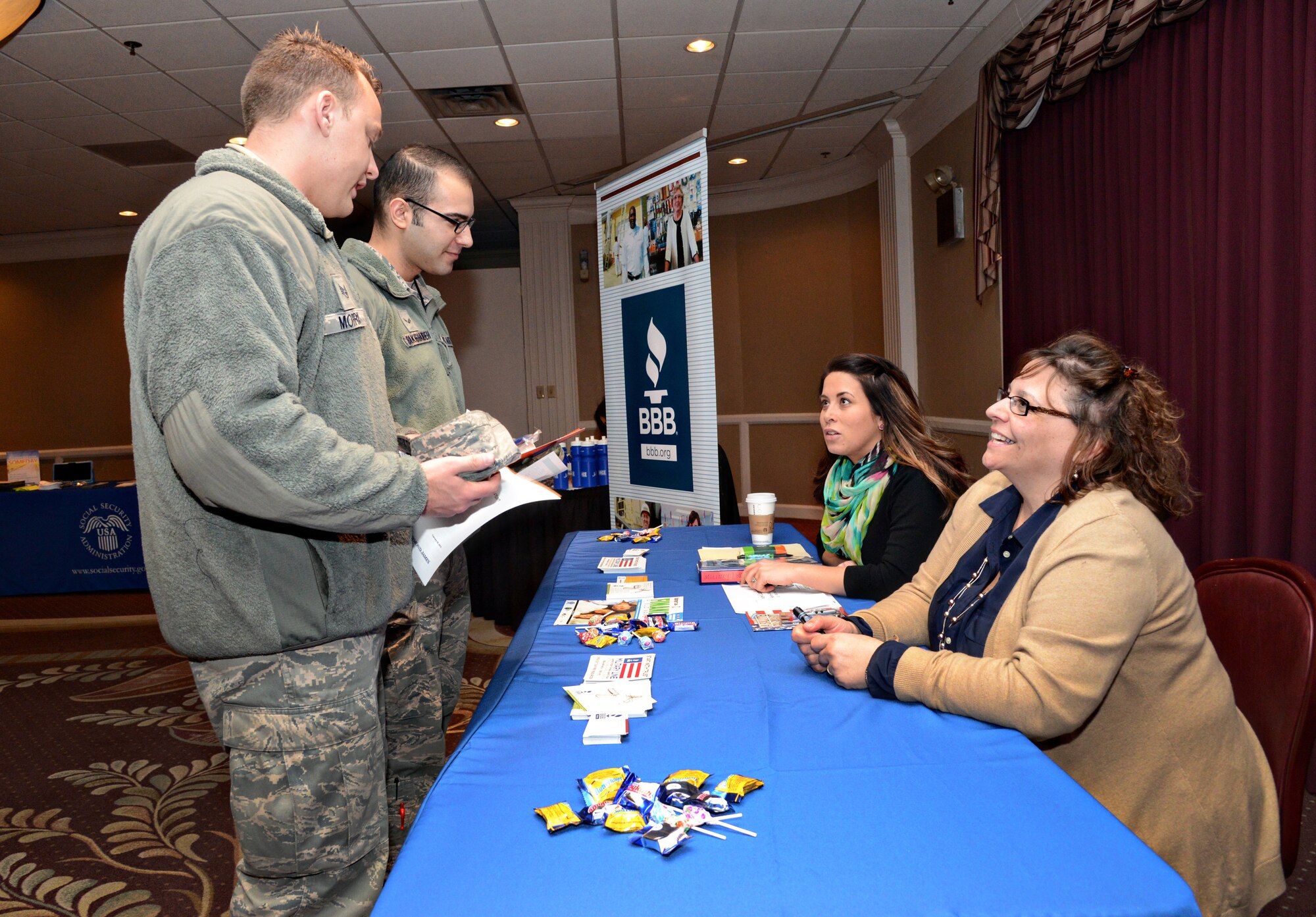 Staff Sgt. Thomas Morris, left, and Airman 1st Class Hassan Bakhshandeh, both 552nd Aircraft Maintenance Squadron members, get information from Kallie Hannish and Tina Smith of the Better Business Bureau during the Airman and Family Readiness Center’s Financial Fair on Feb. 25 at the Tinker Club. (Air Force photo by Kelly White)