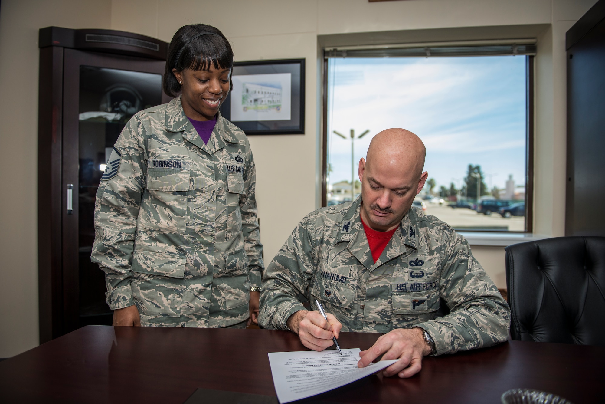 MSgt Denise Robinson, 39th Force Support Squadron Personnel Support for Contingency Operations team chief stands by as Col. Mark Anarumo, 39th Air Base Wing vice commander, signs the Proclamation to kick off Women History Month March 6, 2015, at Incirlik Air Base, Turkey. WHM is celebrated to honor and pay tribute to the accomplishments and achievements of women who served in the Air Force. (U.S. Air Force photo by Cory W. Bush/Released)