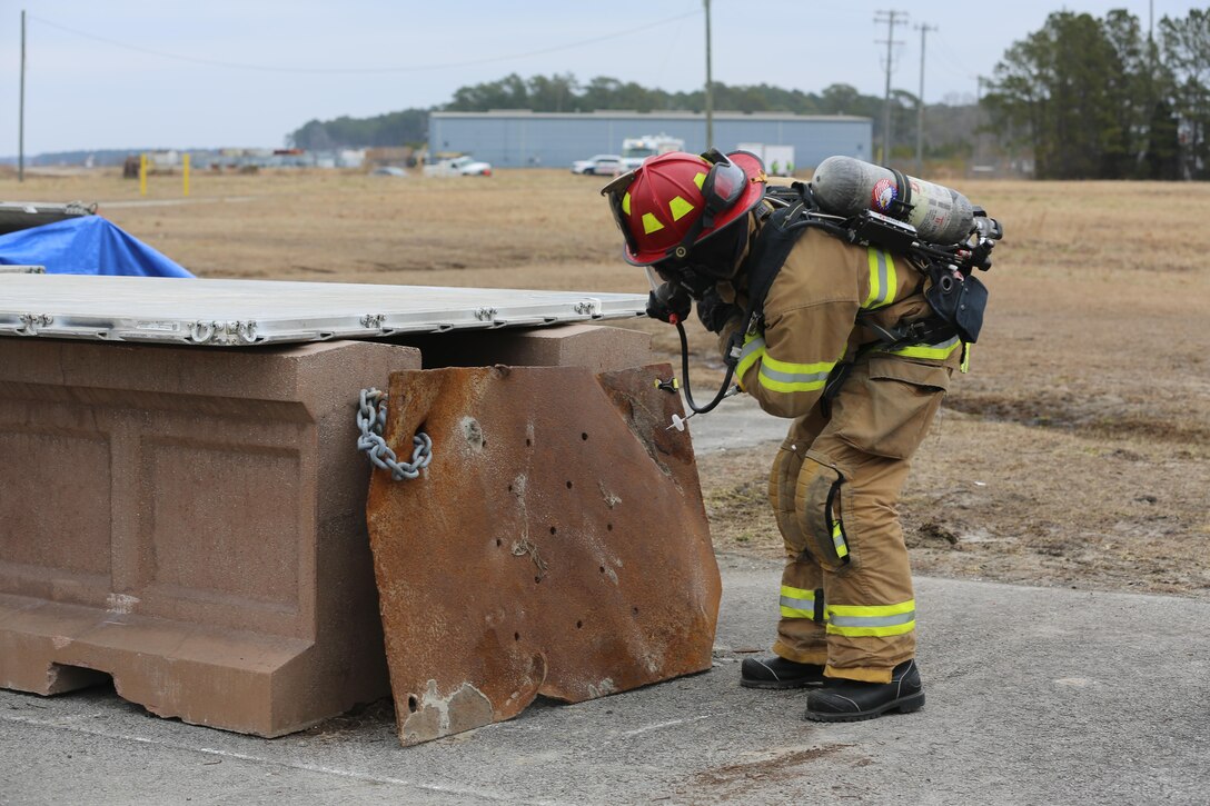 Eddie Hudson looks through a small opening to check for survivors during the 2015 Crisis Response Drill at Marine Corps Air Station Cherry Point, N.C., March 3, 2015.  The annual exercise simulated a vehicle borne IED destroying a main entrance gate and was designed to test Cherry Point’s emergency preparedness program and response procedures. Hudson is a firefighter with the Cherry Point Fire and Rescue Department.