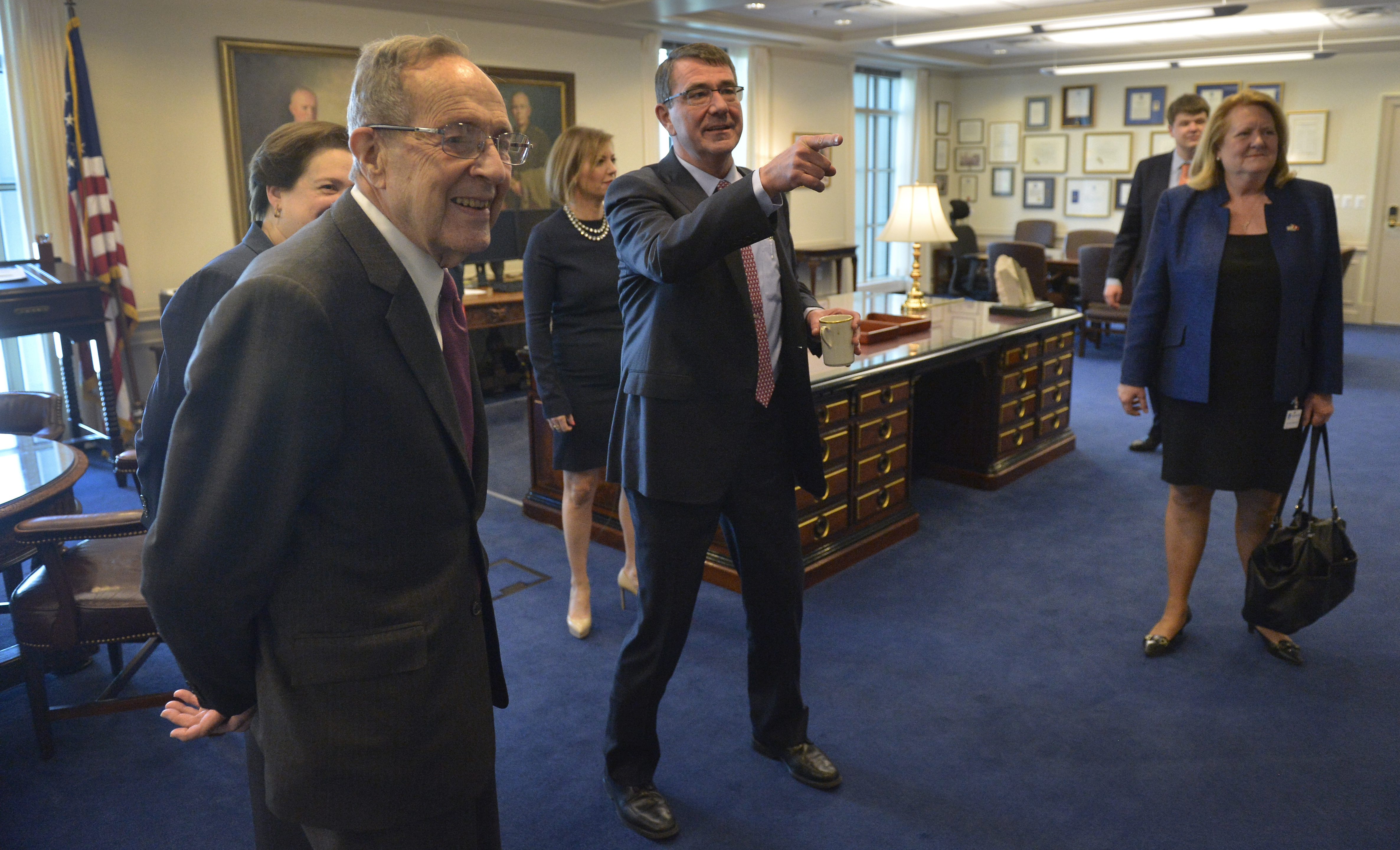 Defense Secretary Ash Carter points to a portrait of William Perry, the  19th defense secretary, as