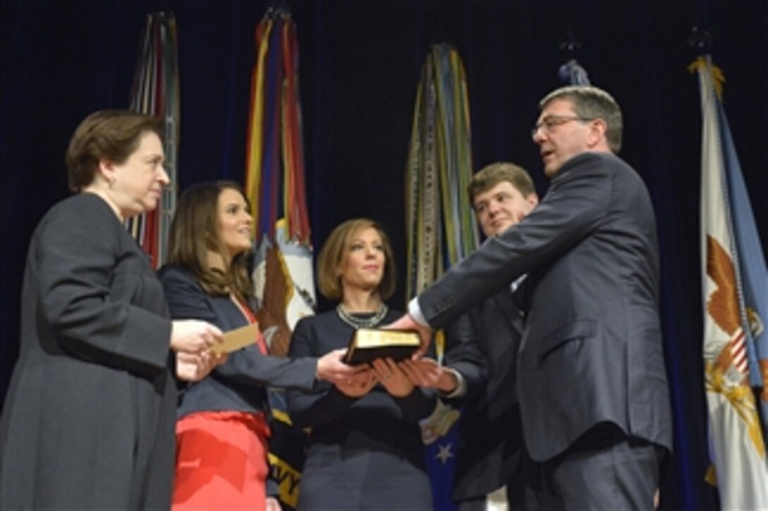 Supreme Court Justice Elena Kagan administers the oath of office to Defense Secretary Ash Carter as his wife, Stephanie, holds the Bible and their children, Ava and Will, look on during a ceremonial swearing-in at the Pentagon, March 6, 2015. Vice President Joe Biden officially swore in Carter as the 25th secretary of defense last month.