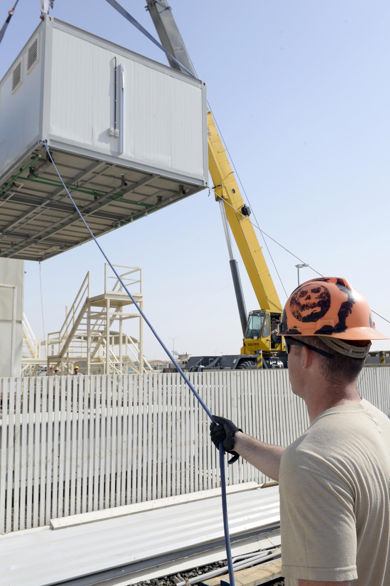 Airman 1st Class Randy, Expeditionary Prime Base Engineer Emergency Force Squadron electrician, assists with lowering a new shower Cadillac into place at an undisclosed location in Southwest Asia Mar. 4, 2015. The EPBS has been working on a variety of projects consisting of a security fence extending around the airfield, replacing about $280K worth of new showers in the Army barracks as well as constructing a 13.5 foot by eight foot, 12 inch thick concrete vault for the Communications Squadron. Randy is currently deployed from the 174th Civil Engineer Squadron out of Hancock Field, Syracuse, N.Y. (U.S. Air Force photo/Tech. Sgt. Marie Brown) (RELEASED)
