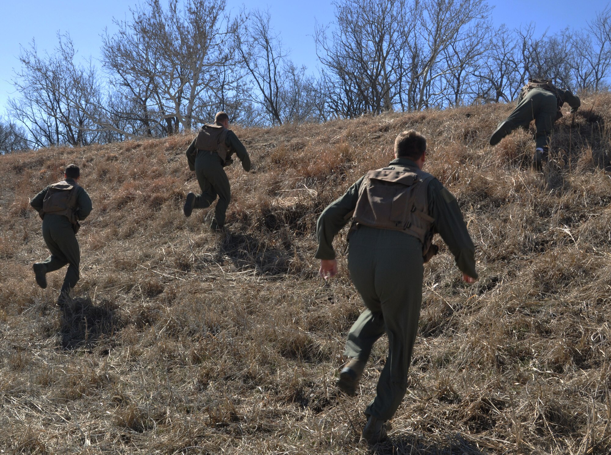McConnell Reservists sprint over a hill  to search for cover during a Survival, Evasion, Resistance, Escape training scenario in a wooded area in Derby, Kan.,  March 7, 2015. The primary focus of this scenario was evasion.  To accomplish this, the reservists simulated an aircraft crash that had landed in enemy territory.  (U.S. Air Force photo by Tech. Sgt. Abigail Klein)
