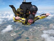 Chief Master Sgt. Thomas Mason parachutes with Army jump team, The Golden Knights, at Homestead Air Reserve Base, Fla., Feb 25.  Mason and the other 10th Air Force command chiefs were at Homestead for the annual Airman of the Year board and workshop.  Mason was one of seven chiefs who had the opportunity to tandem jump with the Army Golden Knights team.  The Golden Knights were at Homestead for their winter training. (U.S. Army photo/Staff Sgt. Richard Sloan)