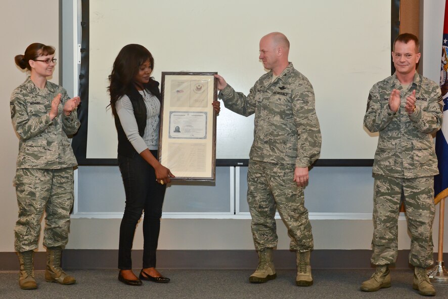 Barbara Timothe of the 139th Operations Group, is presented a plaque from Col. Ed Black, vice commander of the 139th Airlift Wing, to commemorate her recent naturalization as an American citizen.  Timothe moved to the United States from Haiti in 2007 to study political science at Missouri Western State University.  She is planning to attend law school to become an attorney and one day hopes to work for the United Nations.  She became an U.S. citizen during a nationalization ceremony last December.  (U.S. Air National Guard photo by: Senior Airman Patrick P. Evenson/Released)