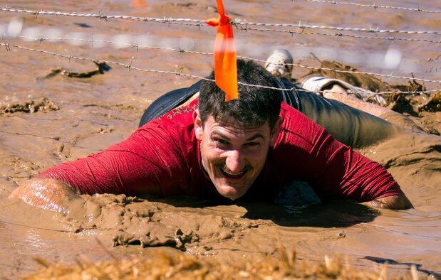 Tech. Sgt. Matthew Place, 919th Special Operations Communications Squadron, low-crawls through mud under barbed wire in the Kiss of Mud challenge during the Tough Mudder in Milton, Fla., March 7. Active duty and reserve service members came out to test their luck in the mud. Tough Mudder is a team-oriented 10-12 mile obstacle course designed to test physical strength and mental grit.  (U.S. Air Force photo/Tech. Sgt. Cheryl Foster)