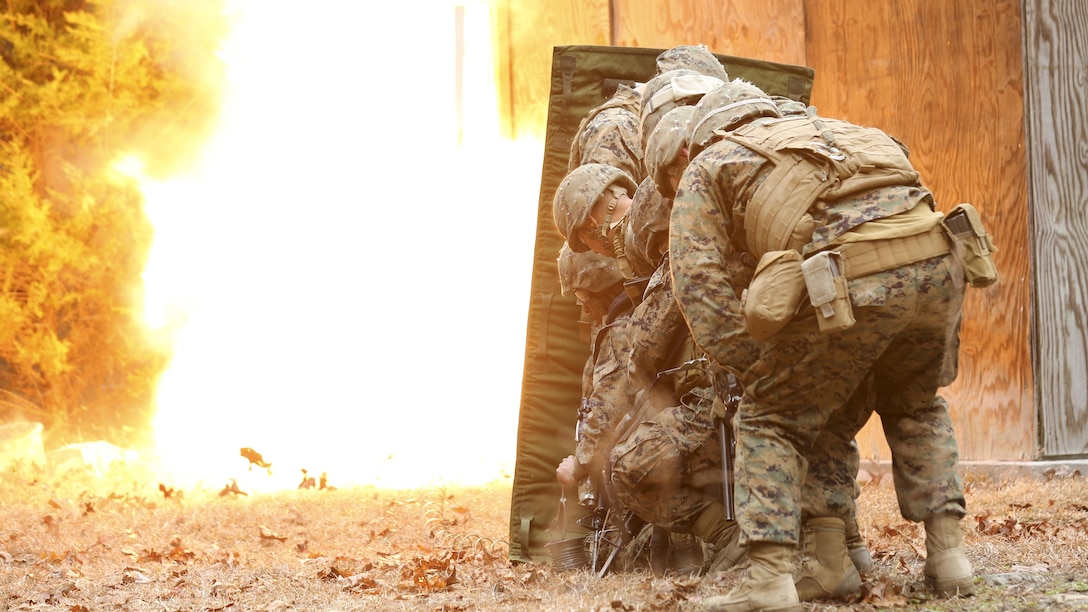 Marines with Mobility Assault Company, 2nd Combat Engineer Battalion, 2nd Marine Division stand behind a blast blanket as detonation cord ignites, blowing the door in and giving them a clear passage to breach the building during an urban breaching course, aboard Camp Lejeune, N.C., March 3, 2015. For each breach, the Marines would stack up behind a blast blanket, which allows them to stand closer to the blast by protecting them from shrapnel and debris. (U.S. Marine Corps photo by Cpl. Justin T. Updegraff)