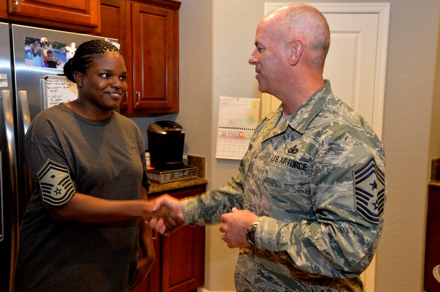 Chief Master Sgt. Butch Brien, 432nd Wing/432nd Air Expeditionary Wing command chief, congratulates Master Sgt. Laquai Knoble, 432nd Operations Support Squadron first sergeant, for reaching senior master sergeant, March 4, 2014.  Leadership from the 432nd WG/432nd AEW made sure that Creech Air Force Base’s newest senior master sergeants and their families were personally recognized for their achievements with an unexpected visit at their homes. (U.S. Air Force photo by Senior Airman Adarius Petty/Released)