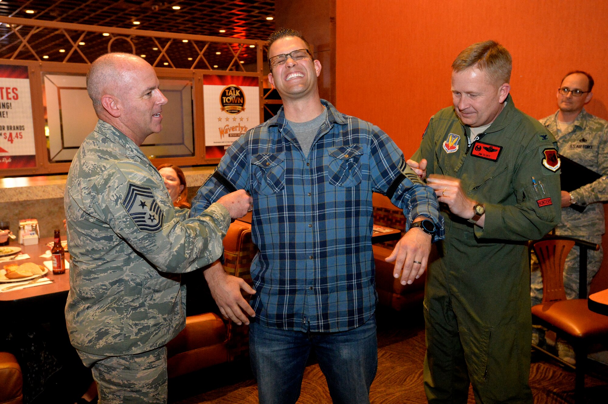 Chief Master Sgt. Butch Brien, 432nd Wing/432nd Air Expeditionary Wing command chief, left, and Col. James Cluff, 432nd WG/432nd AEW commander, right, congratulates Master Sgt. Guenther Bogensperger, 432nd Aircraft Maintenance Squadron first sergeant, with his new senior master sergeant rank at the Deployed Spouses dinner, March 4, 2014.  Bogensperger was 1 of 6 selectees on Team Creech. (U.S. Air Force photo by Senior Airman Adarius Petty/Released)