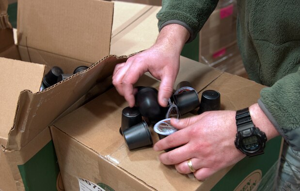 Chaplain (Capt.) Thomas Fussell, 90th Missile Wing chaplain, inspects coffee pods March 3, 2015, in the 90th Logistics Readiness Squadron cargo area on F.E. Warren Air Force Base, Wyo. The coffee will be distributed with coffee machines to break rooms, training rooms and mission ready rooms Airmen visit before heading out to the field. (U.S. Air Force photo by Airman 1st Class Malcolm Mayfield)