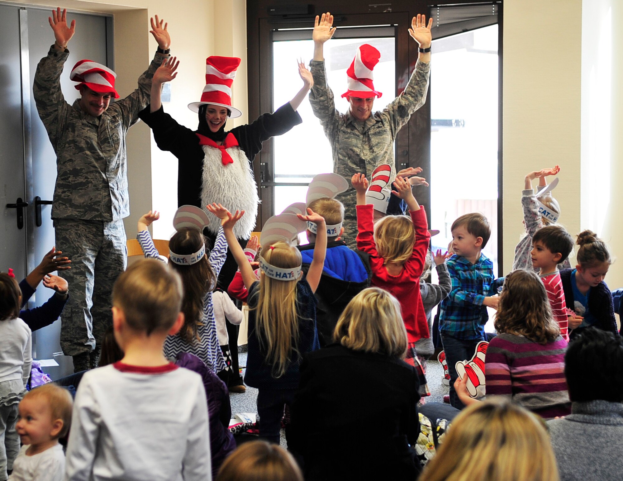 Chief Master Sgt. Steven Mandell, (left), 86th Force Support Squadron superintendent, Alison McKee, 86th FSS librarian, and Lt. Col. Thomas Ausherman, (right), 86th FSS commander, lead children through a song and dance during Read Across America, March 5, 2015, at Ramstein Air Base, Germany. The event consisted of story-time, snacks and free books for the children. (U.S. Air Force photo/Airman 1st Class Larissa Greatwood)