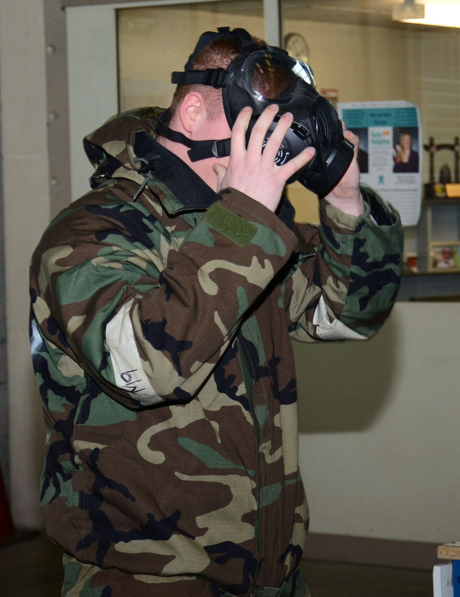 U.S. Air Force Airman 1st Class James Brewer, 100th Logistics Readiness Squadron Individual Protective Equipment mobility apprentice from Shawnee, Okla., demonstrates how to effectively put on his gas mask to civilians from the 100th LRS during a Civilian Appreciation Day tour Feb. 27, 2015, on RAF Mildenhall, England. Brewer explained how this equipment would be used in real-world situations and why he needs to get the items on as quickly as possible in case of a chemical attack. (U.S. Air Force photo by Gina Randall/Released)