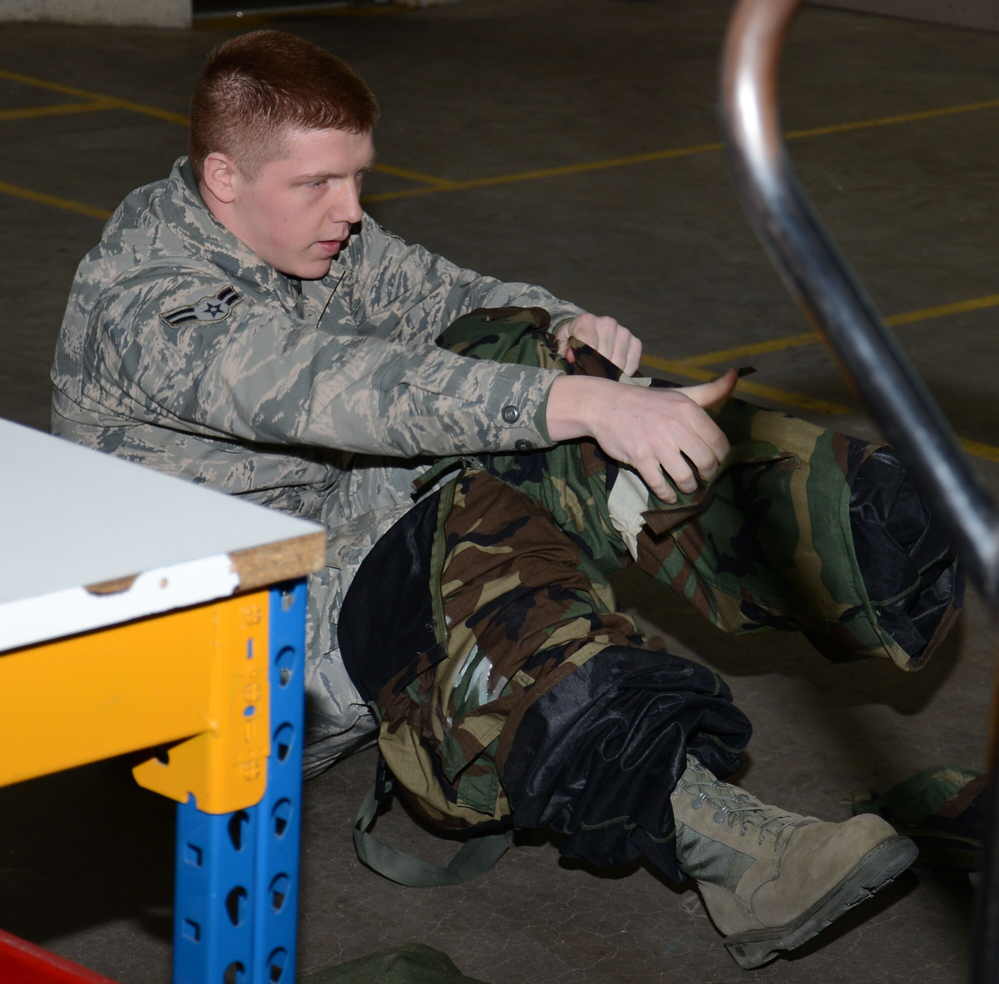 U.S. Air Force Airman 1st Class James Brewer, 100th Logistics Readiness Squadron Individual Protective Equipment mobility apprentice from Shawnee, Okla., demonstrates how to effectively put on his chemical protection equipment to civilians from the 100th LRS during a tour for Civilian Appreciation Day Feb. 27, 2015, on RAF Mildenhall, England. Brewer took less than two minutes to dress in his full mission-oriented protective posture gear. (U.S. Air Force photo by Gina Randall/Released)