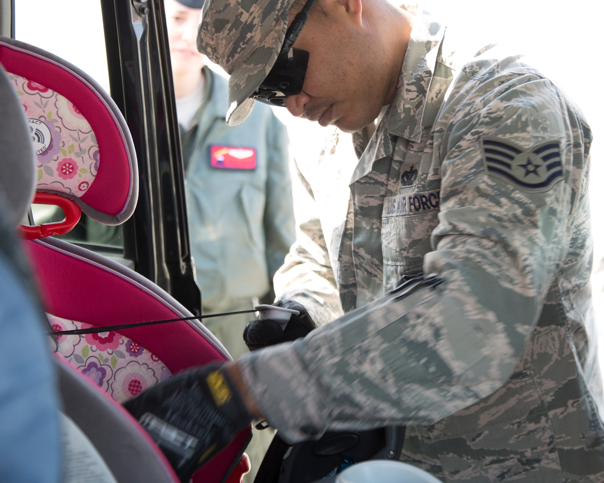 Staff Sgt. Trevor Alexis, 374th Civil Engineer Squadron fire department NCO in charge of training, inspects a child safety seat for a driver at Yokota Community Center, March 4, 2015.  Alexis is a certified child passenger safety technician. (U.S. Air Force photo by Osakabe Yasuo/Released)