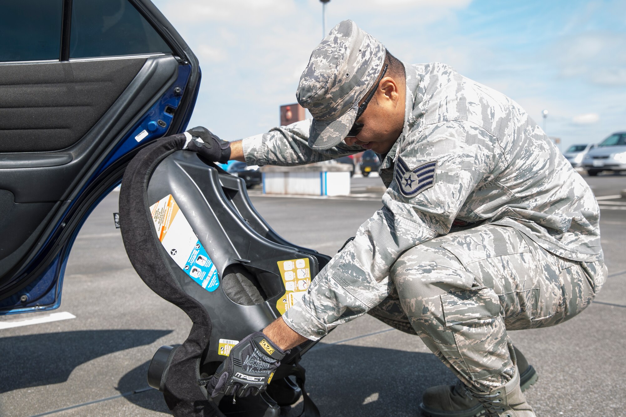 Staff Sgt. Trevor Alexis, 374th Civil Engineer Squadron fire department NCO in charge of training, helps install a child safety seat for a driver at Yokota Community Center, March 4, 2015.  Alexis is a certified child passenger safety technician. (U.S. Air Force photo by Osakabe Yasuo/Released) 