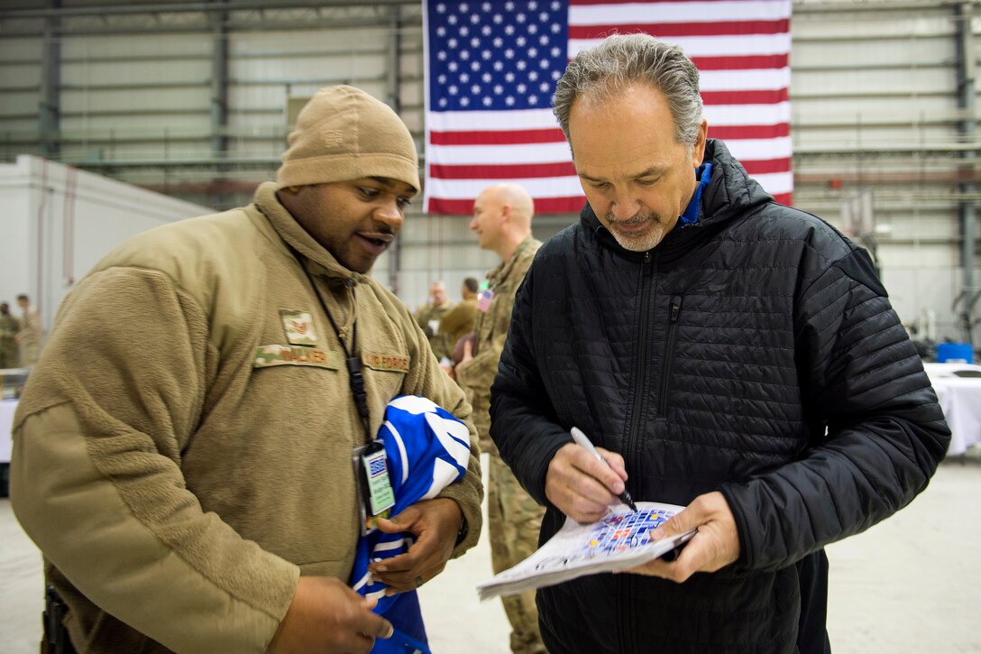 Indianapolis Colts head coach Chuck Pagano, right, signs a program for a U.S. service member after USO concert on Bagram Airfield, Afghanistan, March 6, 2015. 