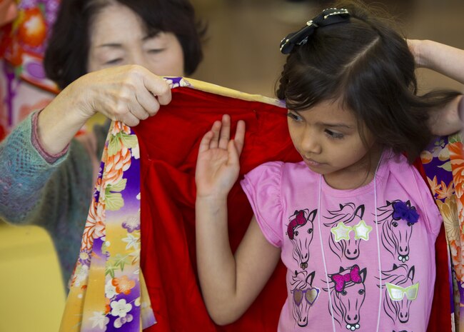 A Japanese volunteer helps a visitor from School Age Care aboard Marine Corps Air Station Iwakuni, Japan, put on a Japanese kimono during the Hina Doll Festival in Shunan City, March 7, 2015. The Hina Doll Festival, or Hinamatsuri, is a day in Japan when parents celebrate their daughters’ happiness, growth and good health and is usually held on March 3.