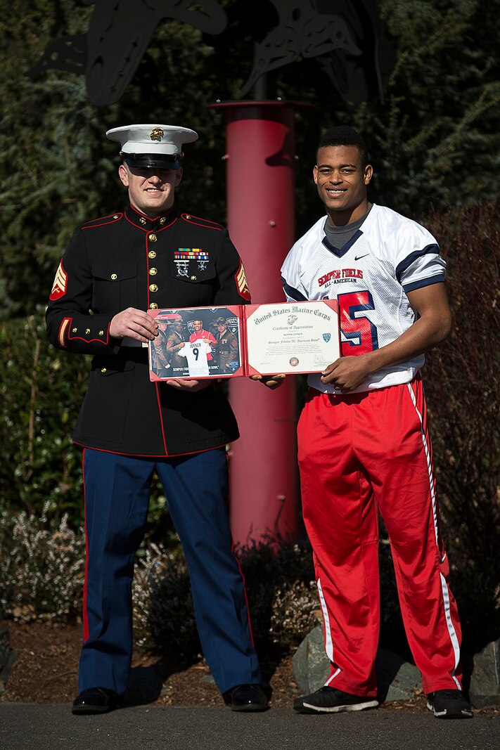 Sgt. Jeff Otterson, a Marine recruiter in Marysville, Washington, congratulates Marysville-Pilchuck High School student athlete Austin Joyner on his participation in the Semper Fidelis All-American Bowl March 9, 2015. Joyner, a highly-touted cornerback from Marysville, was one of three Washington State football players selected to play in the Jan. 4 game in Carson, California. Following his high school graduation, Joyner will attend the University of Washington on an athletic scholarship. (U.S. Marine Corps photo by Sgt. Reece Lodder)