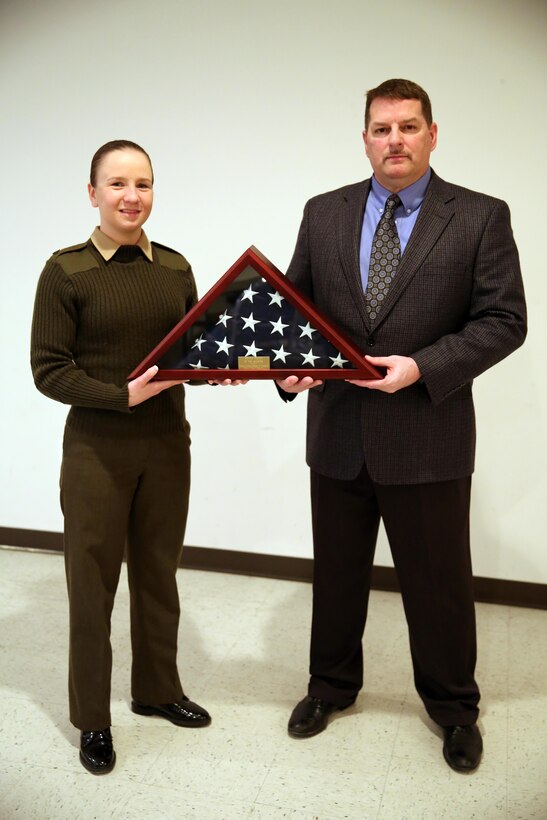 Cpl. Grace Waladkewics, left, and Mike Barton display an encased flag during the Service Person of the Quarter luncheon in Morehead City, N.C., Feb. 20, 2015. The Carteret County Chamber of Commerce honored Waladkewics for her volunteer service and being a positive role model in the local community. Waladkewics is a combat correspondent and Barton is the director, both with the Joint Public Affairs Office at Marine Corps Air Station Cherry Point. 