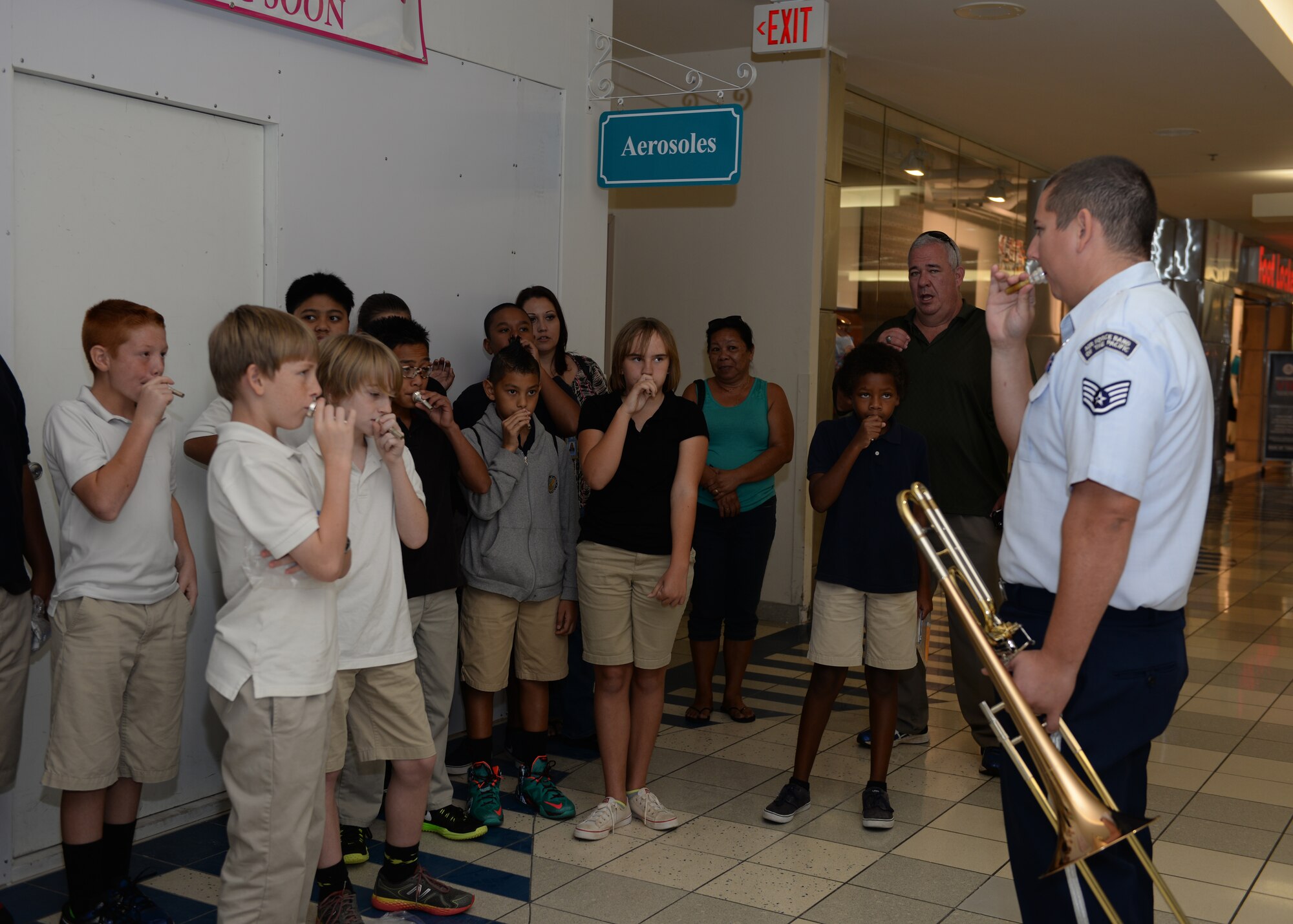 Staff Sgt. Ryan Terronez, musician, Air Force Band of the Pacific’s Papana, Joint Base Pearl Harbor Hickam, HI, shows Department of Defense Education Activity school band children how to use a trombone mouth piece after a performance Mar. 10, 2015, at the Micronesia Mall in Dededo, Guam. The Air Force Band of the Pacific’s Papana supports the U.S. Pacific command strategies of partnership, readiness and presence by conducting protocol, community and nation-building missions throughout the pacific. (U.S. Air Force photo by Senior Airman Cierra Presentado/Released)