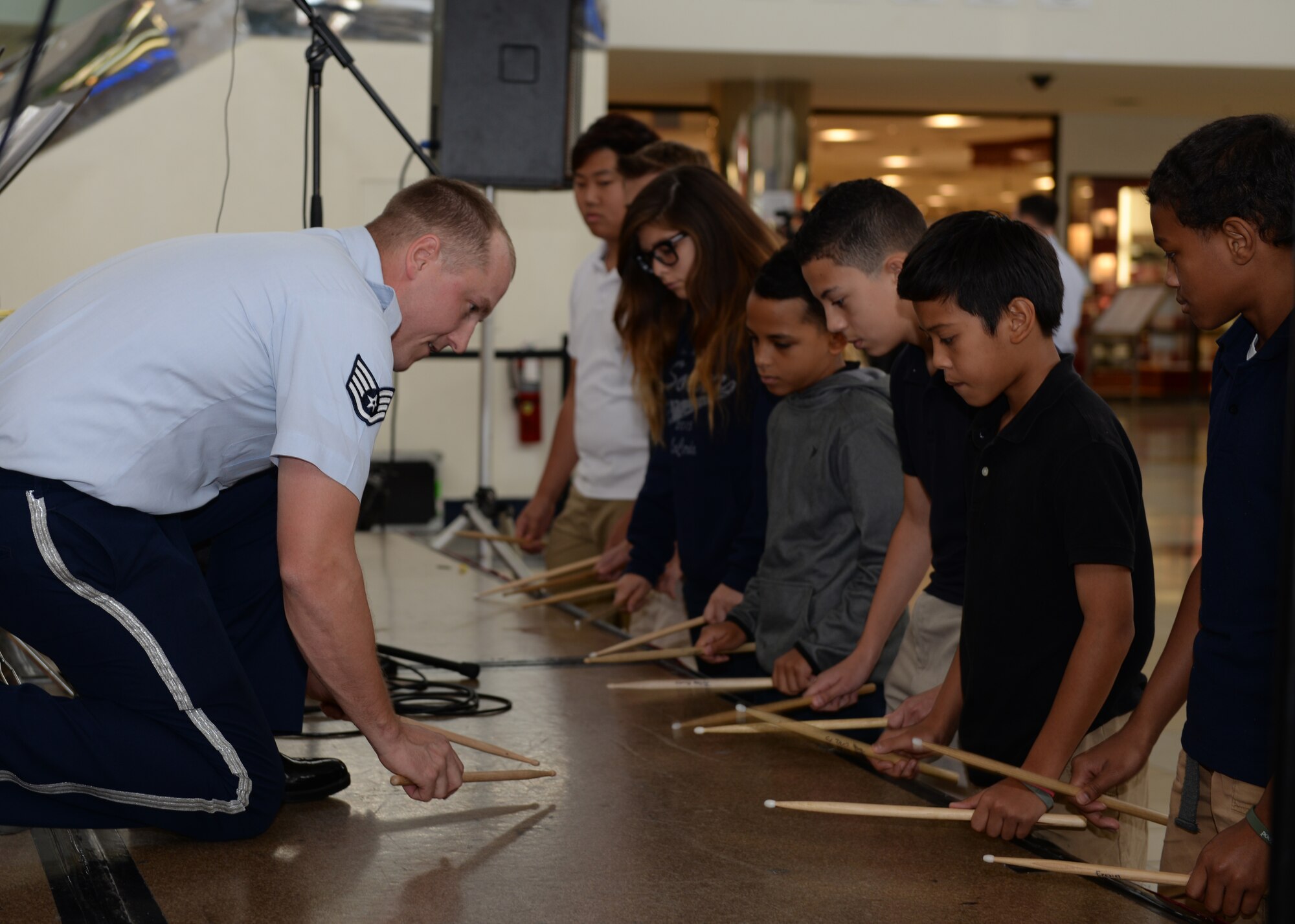 Staff Sgt. Brandon Richard, musician, Air Force Band of the Pacific’s Papana, Joint Base Pearl Harbor Hickam, HI, shows Department of Defense Education Activity school band children how to use percussion sticks after a performance Mar. 10, 2015, at the Micronesia Mall in Dededo, Guam. The Air Force Band of the Pacific’s Papana supports the U.S. Pacific command strategies of partnership, readiness and presence by conducting protocol, community and nation-building missions throughout the pacific. (U.S. Air Force photo by Senior Airman Cierra Presentado/Released)