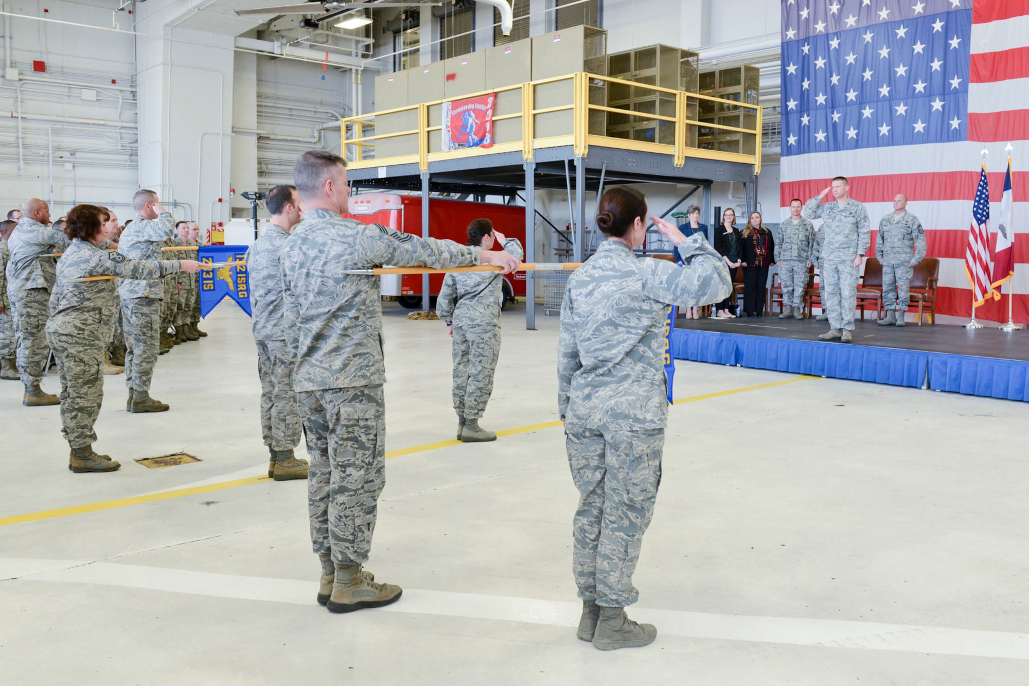 Members of the 132d Wing (132WG), Des Moines, Iowa Intelligence Surveillance Reconnaissance Group (ISRG) (front, saluting) give their first salute to Col. Mark Chidley (back, standing on stage saluting), 132WG ISRG Commander, during the 132WG ISRG Activation Ceremony held in the 132WG Fire House on Saturday, March 7, 2015.  This ceremony formally recognizes the official activation of the 132WG ISRG.  (U.S. Air National Guard photo by Senior Airman Michael J. Kelly/Released)