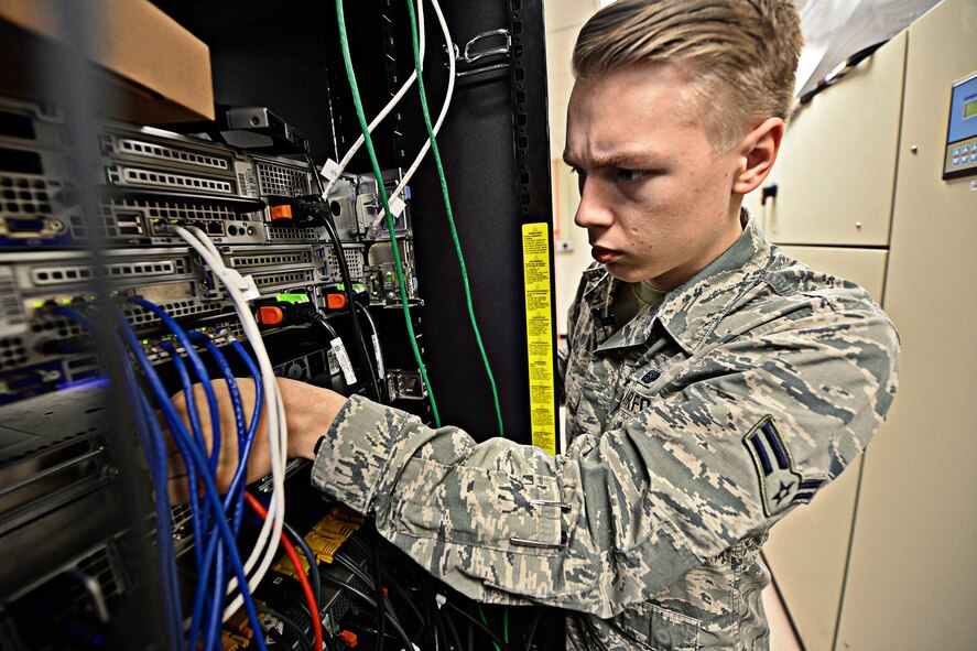 Airman 1st Class Brandon Koch, 28th Communications Squadron cyber systems operator, adjusts cables in a server room at Ellsworth Air Force Base, S.D., March 3, 2015. Cyber systems specialists develop and maintain foundational communication capabilities by providing network services, including messaging, share drives, network access and storage to the base. (U.S. Air Force photo by Airman 1st Class Zachary Hada/Released)