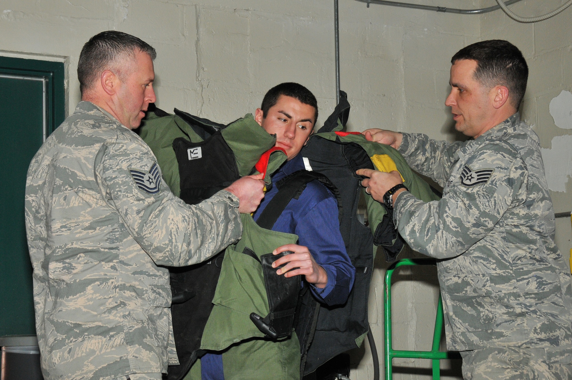 A picture of Tech. Sgt. John Hurley and Staff Sgt. Joseph Coates, 177th Fighter Wing Explosive Ordinance Disposal, assisting a member of a youth advisory council don of a bomb suit.