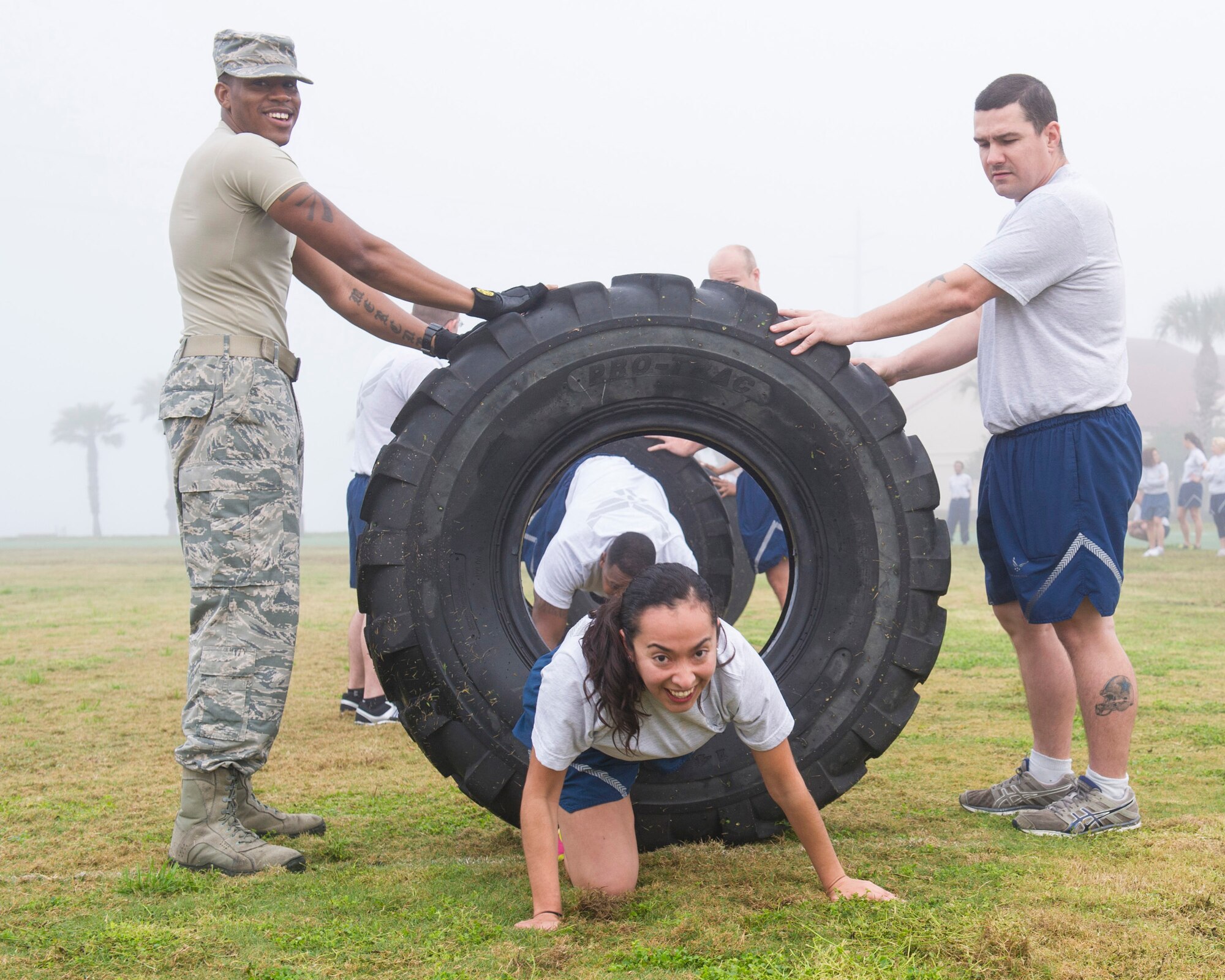 Tech. Sgt. James Norton, 45th Space Wing Safety, and Tech. Sgt. Harry Goldsboro, 920th Operations Support Squadron, hold a tire as Senior Airman Becky Guzman, 45th Comptroller Squadron, crawls through during the Women’s History Month Kick-off Obstacle Course event March 2, 2015 at Warfit Field on Patrick Air Force Base, Fla. (U.S. Air Force photo/Matthew Jurgens)