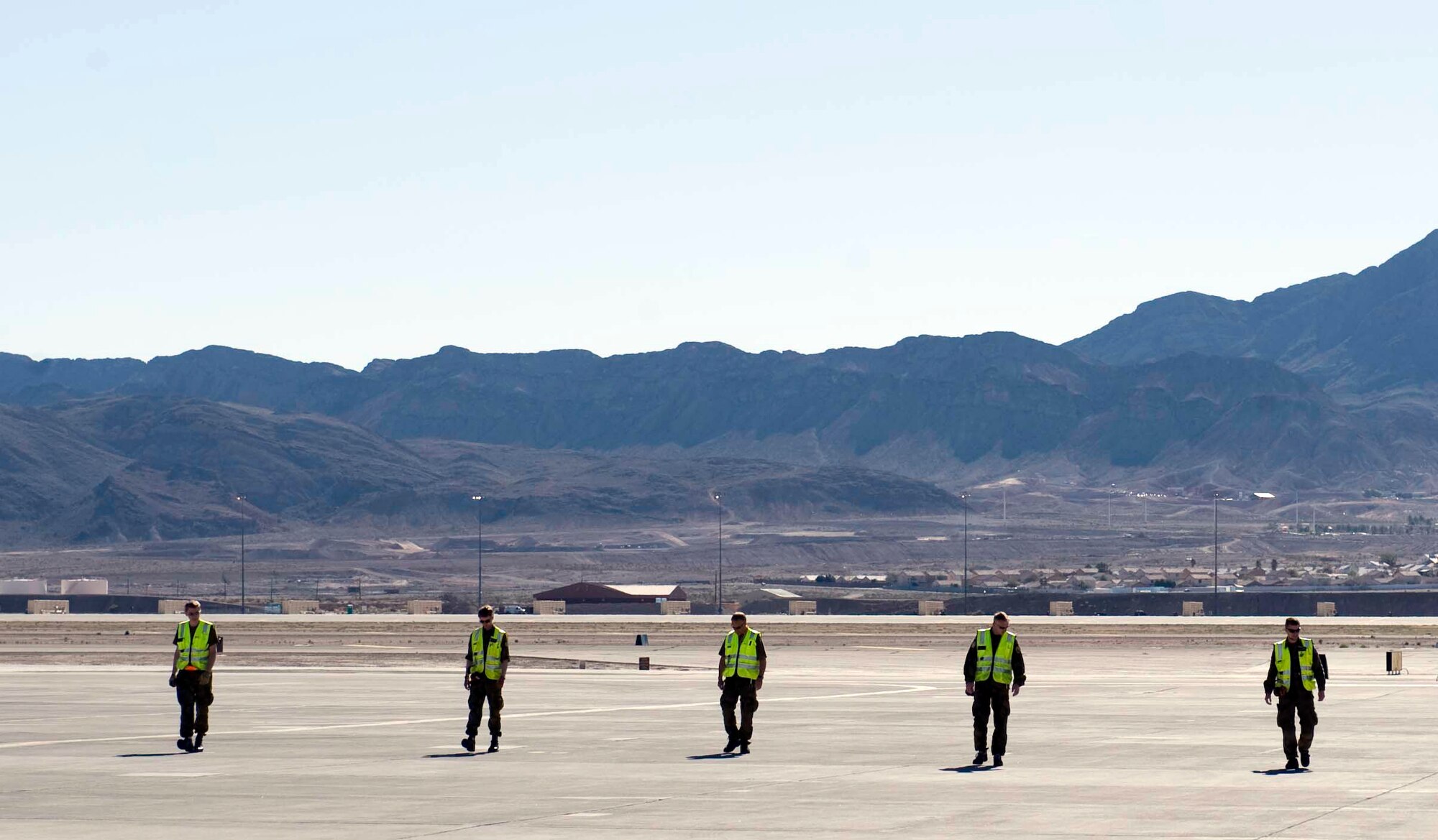 Members of the Royal Norwegian air force perform a foreign object damage walk during Red Flag 15-2, to check for hazardous materials along the flightline at Nellis Air Force Base, Nev., March 5, 2015. FOD walks are performed to ensure debris or foreign objects are removed from the flightline that could potentially damage aircraft assets. (U.S. Air Force photo by Airman 1st Class Rachel Loftis)