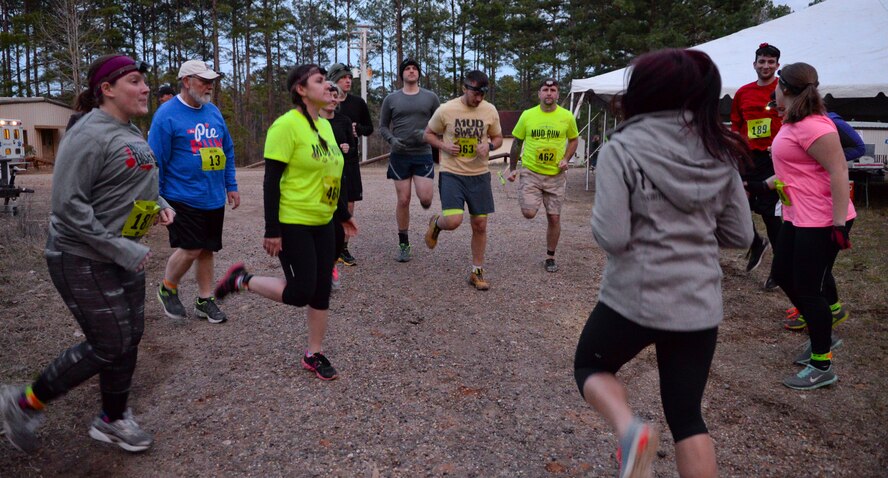 Runners in the final wave of the mud run perform warm-up exercises on Barksdale Air Force Base, La., March 7, 2015. The night wave provided an extra challenge with lower visibility for runners. Emergency personnel were on hand in the event of a mishap. (U.S. Air Force photo/Senior Airman Benjamin Raughton)