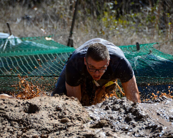Airman 1st Class Devin Talton, 26th Operational Weather Squadron forecaster, crawls under a web during the Defenders of Liberty Mud Run on Barksdale Air Force Base, La., March 7, 2015. The Mud Run featured obstacles, food, games and a bonfire. (U.S. Air Force photo/Senior Airman Benjamin Raughton)
