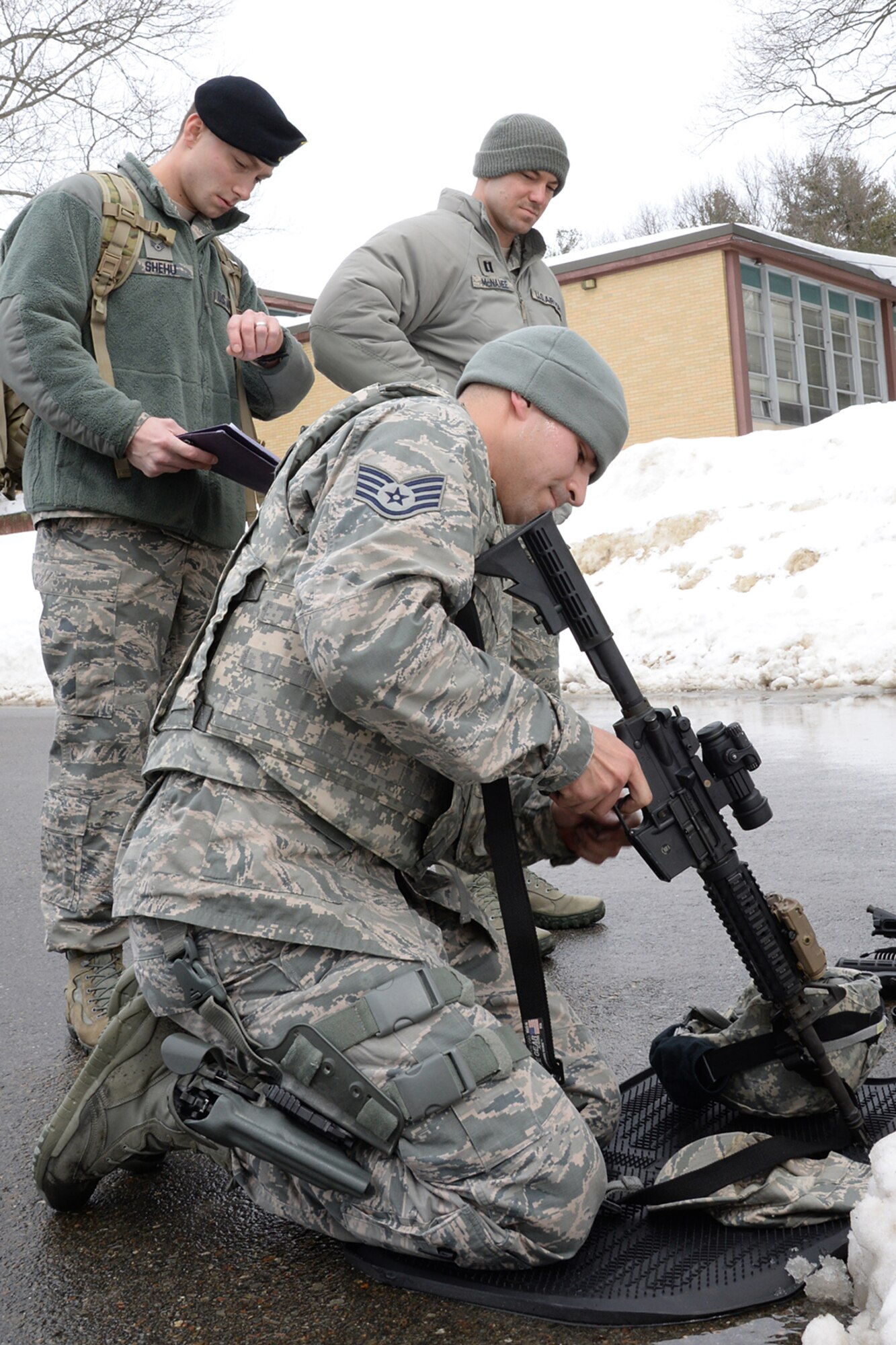 Under the watchful eye of Staff Sgt. Meldion Shehu (left), 66th Security Forces Squadron desk sergeant, and Capt. Christopher J. McNamee, 66 SFS operations officer, Staff Sgt. Jesse Scego, (kneeling), 66 SFS element leader, participates in a weapons assembly portion of a Hanscom Special Reaction Team tryout on base March 4. An SRT team is a specialized team that responds to high-risk situations on a military base. Those trying out were required to pass written exams, weapons proficiency and tests of physical and mental endurance. (U.S. Air Force photo by Linda LaBonte Britt)