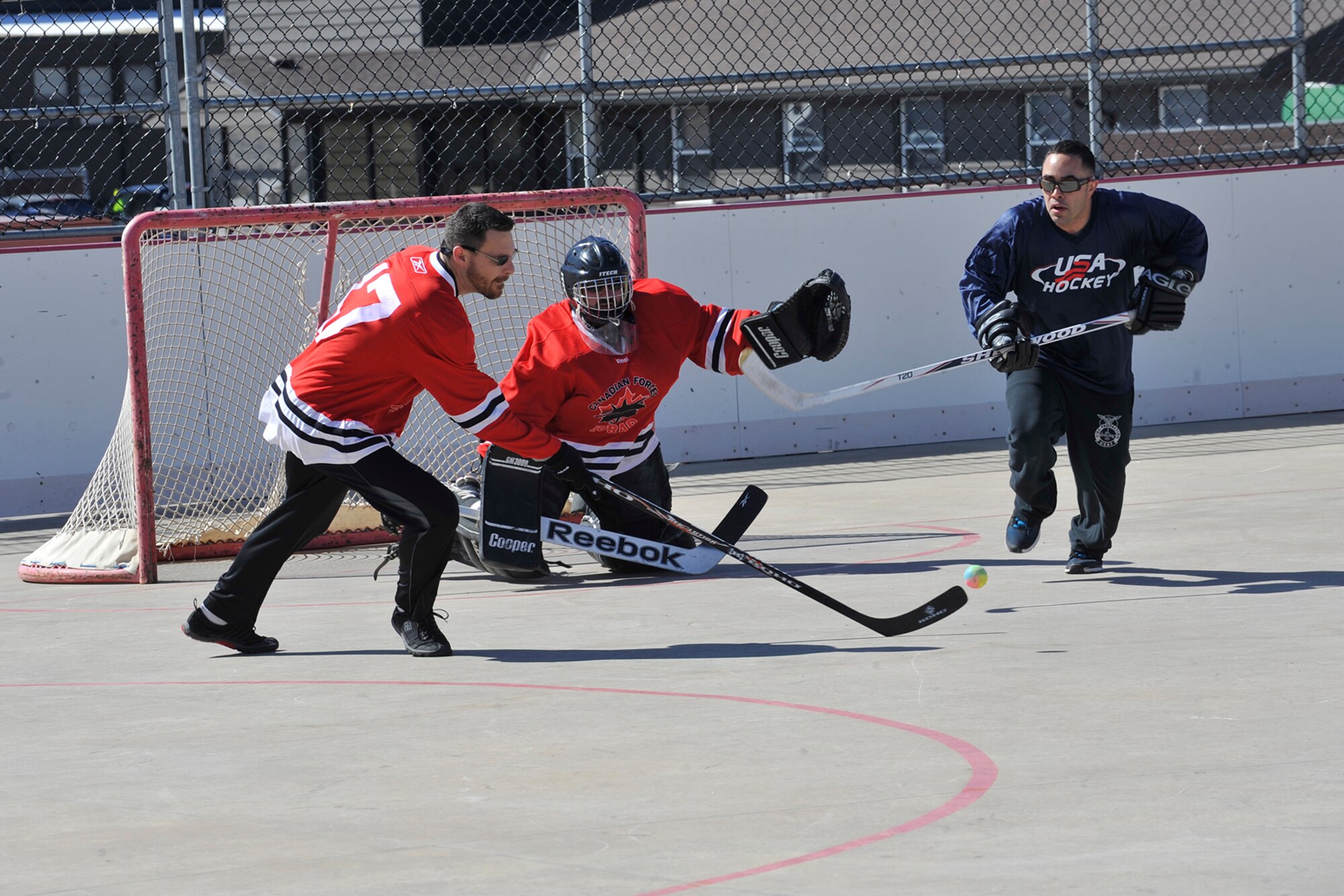 PETERSON AIR FORCE BASE, Colo. --Andrew Wind, Team Canada, clears the net, pushing the ball away from Staff Sgt. Vincent Tafuro, Team USA during the second annual Team USA vs. Team Canada ball hockey tournament at the base hockey rink, Mar. 6. The two teams faced off in a “best-of-three” style tournament, in which Team Canada retained their title of champions.