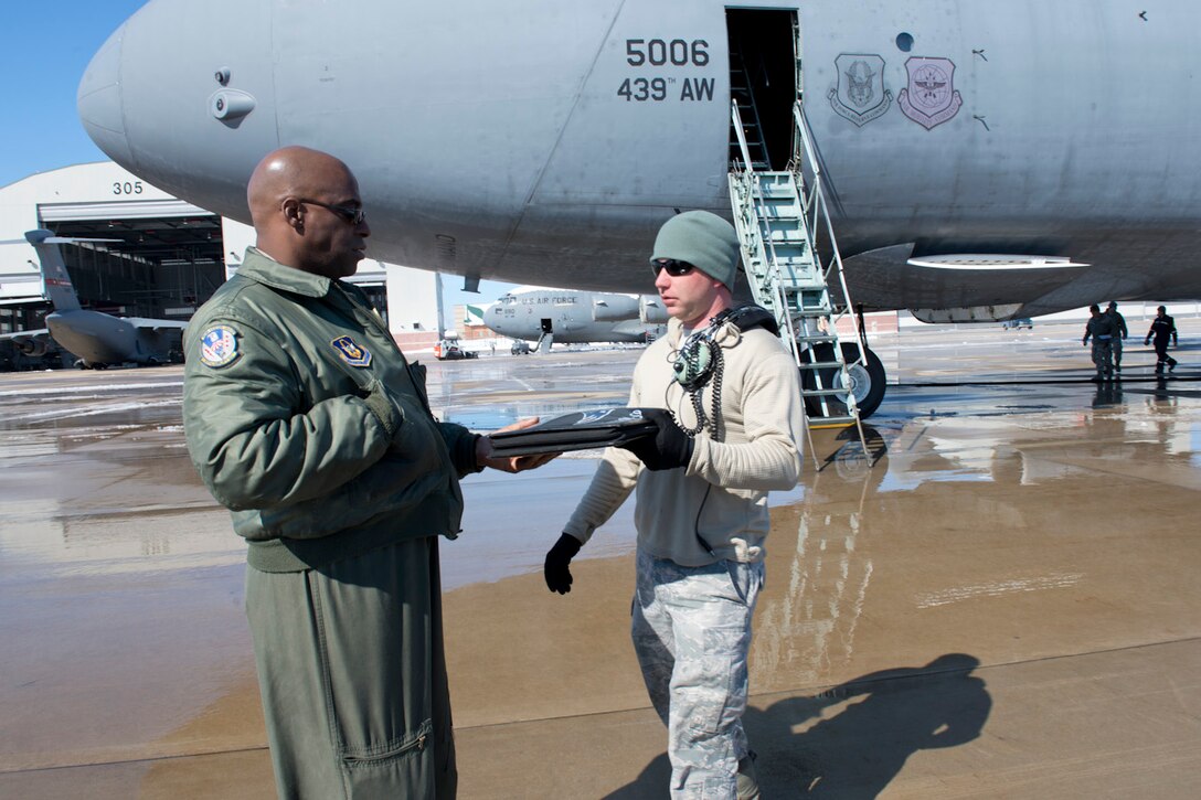 Aircraft maintainer Tech Sgt. Jospeh Kidwell, right, hands aircraft forms for a C-5 aircraft to Master Sgt.Gerald Overton, a flight engineer from the 439th Airlift Wing, March 6 marking the end of the isochronal inspection program at the 167th Airlift Wing. The C-5 from Westover Air Reserve Base was the final aircraft to undergo an isochronal inspection at the Martinsburg Air National Guard Base.(Air National Guard photo by Master Sgt. Emily Beightol-Deyerle)