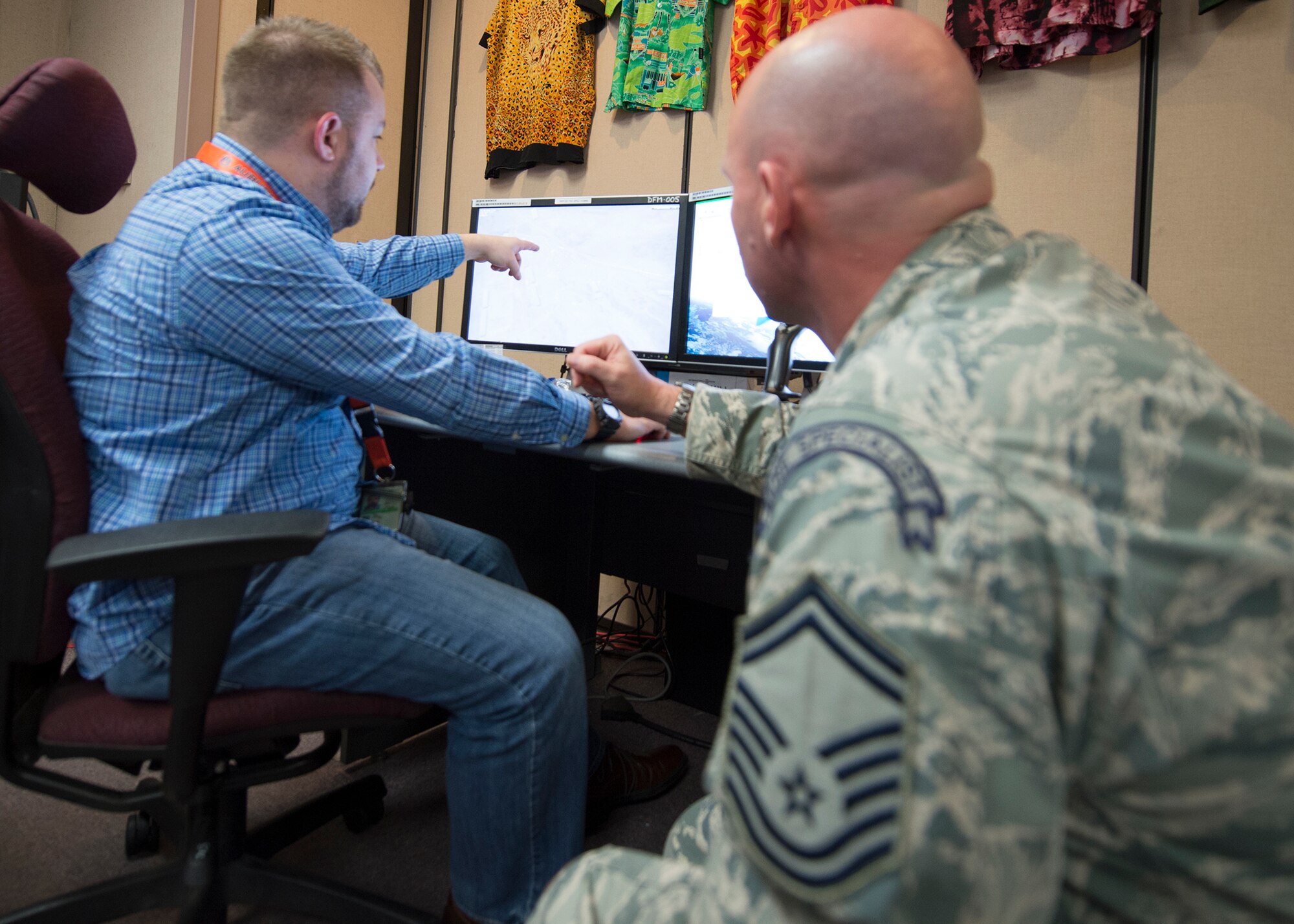 A U.S. Air Force survival, evasion, resistance and escape specialist and a civilian from the Republic of Korea Air Force Simulation Center produce a "troops in contact" rescue scenario March 9, 2015, for exercise Key Resolve at Osan Air Base, Republic of Korea. The exercise is mostly computer based, offering participants the opportunity to respond to varying scenarios to produce close to real-life responses. (U.S. Air Force photo by Staff Sgt. Shawn Nickel/Released)