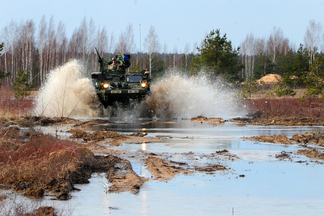 A U.S. Army Stryker armored vehicle splashes through a swamp area as it moves to an objective during a combined live-fire exercise with the Latvian land forces, part of Operation Atlantic Resolve in Adazi training area, Latvia, March 6, 2015. 
