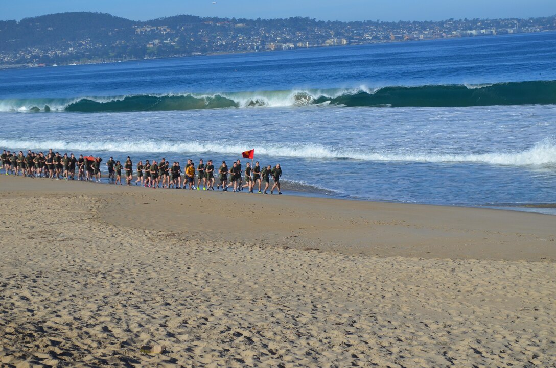 On February 13, 2015 the Marines of Marine Corps Detachment, Presidio of Monterey conducted a 6-mile run along the surf on Del Monte Beach.  Each major section carried a log of approximately 150 lbs, rotating as necessary for full participation.  Pictured here is the front echelon with a panoramic view of the Monterey Peninsula coastline in the background.