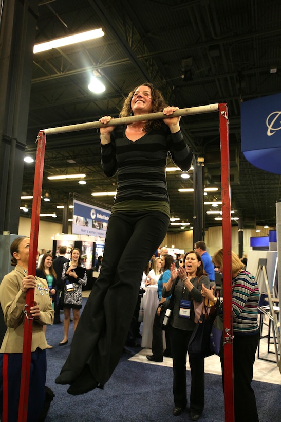 An attendee of the 2015 Women in Aviation National Symposium Event attempts to execute pull-ups at the Marine exhibit at WAI in Dallas, Texas, March 5. Marines attended WAI as a way to expose young men and women to aviation career options in the Marine Corps.
