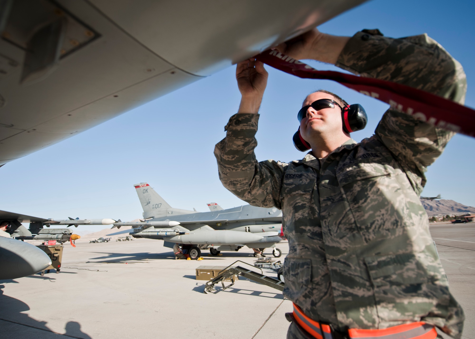 Staff Sgt. Derek Rogers, crew chief assigned to the 125th Aircraft Maintenance Squadron, Tulsa Air National Guard Base, Okla., attaches a “remove before flight” streamer on an F-16 Fighting Falcon during Red Flag 15-2 at Nellis Air Force Base, Nev., March 6, 2015. Red Flag is a realistic combat training exercise involving the air, space and cyber forces of the U.S. and its allies, and is conducted on the vast bombing and gunnery ranges on the Nevada Test and Training Range during day and night operations. (U.S. Air Force photo by Staff Sgt. Siuta B. Ika)