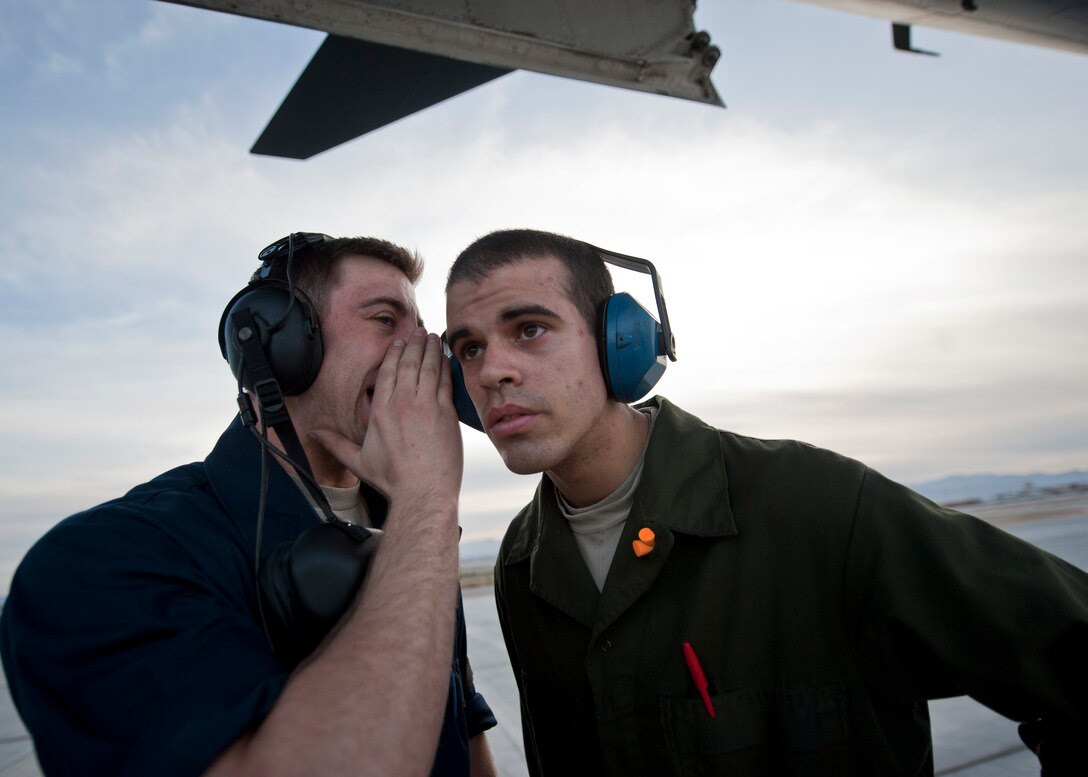 Airman 1st Class Gabriel Henry yells to Airman 1st Class Brian Allen, both crew chiefs assigned to the 28th Aircraft Maintenance Squadron, Ellsworth Air Force Base, S.D., during Red Flag 15-2 at Nellis AFB, Nev., March 10, 2015. Any personnel located in the area of an aircraft with an engine on must wear hearing protection among other personal protective equipment. (U.S. Air Force photo by Staff Sgt. Siuta B. Ika)