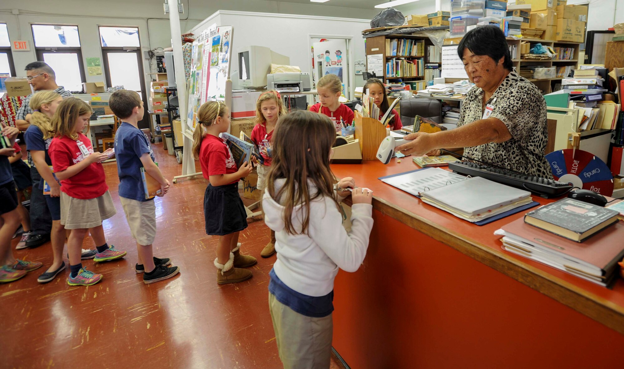 Reva Dacanay, Hickam Elementary School librarian, checks out a book to a student during the school’s annual Read Across America event at Joint Base Pearl Harbor-Hickam, Hawaii, March 6, 2015. The week-long event celebrates the life and contributions of Dr. Seuss, while also encouraging children and teens to read. (U.S. Air Force photo by Tech. Sgt. Terri Paden/RELEASED)